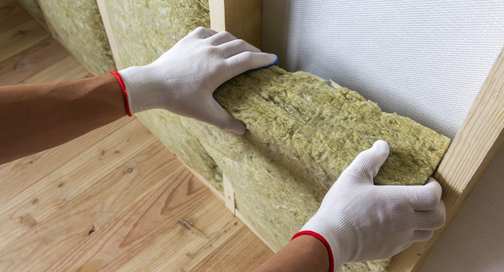 Close-up of worker hands in white gloves insulating rock wool insulation staff in wooden frame for future walls for cold barrier. Comfortable warm home, economy, construction and renovation concept.